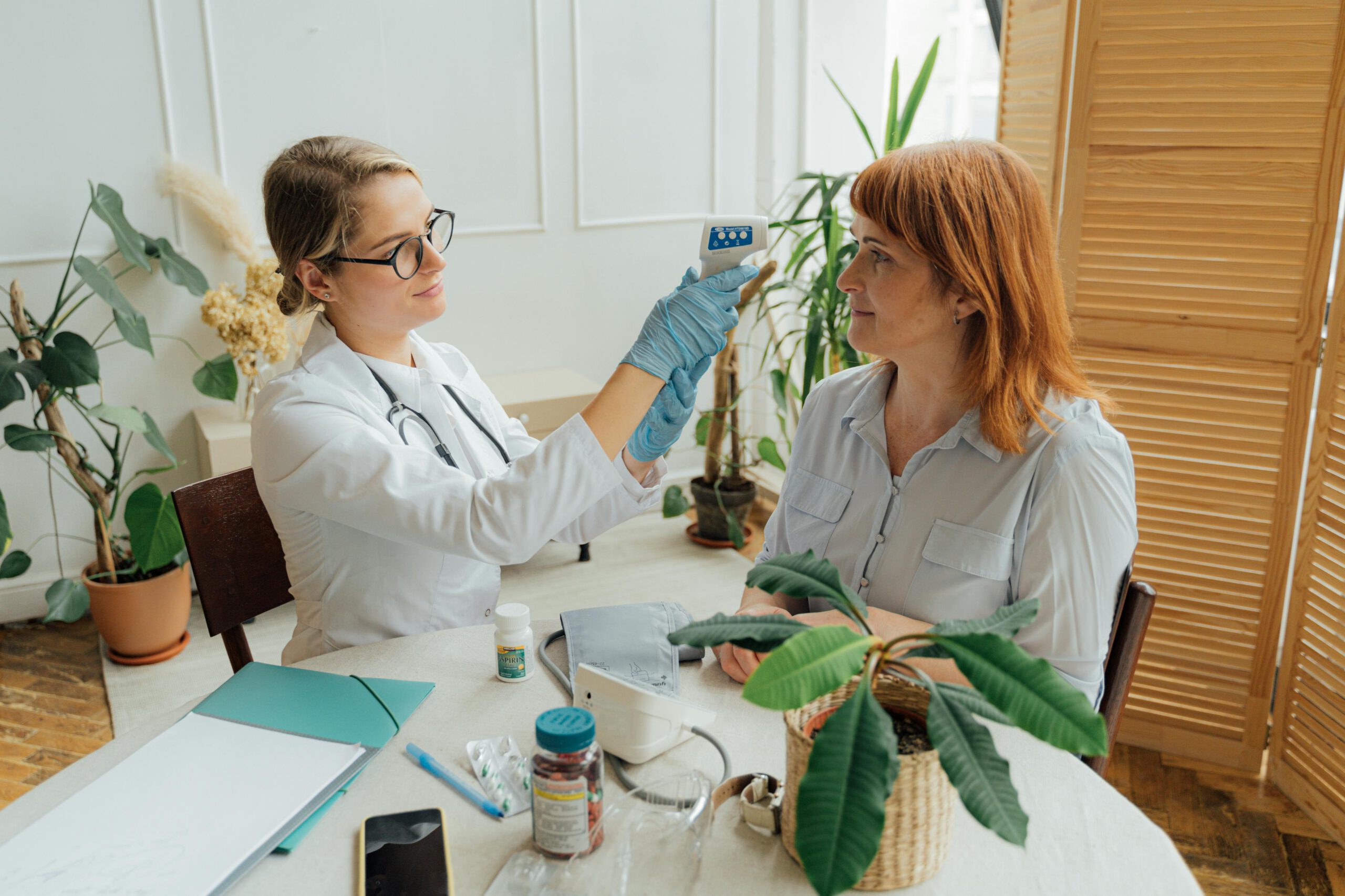 A female doctor sitting with a female patient in her home administering medicine.