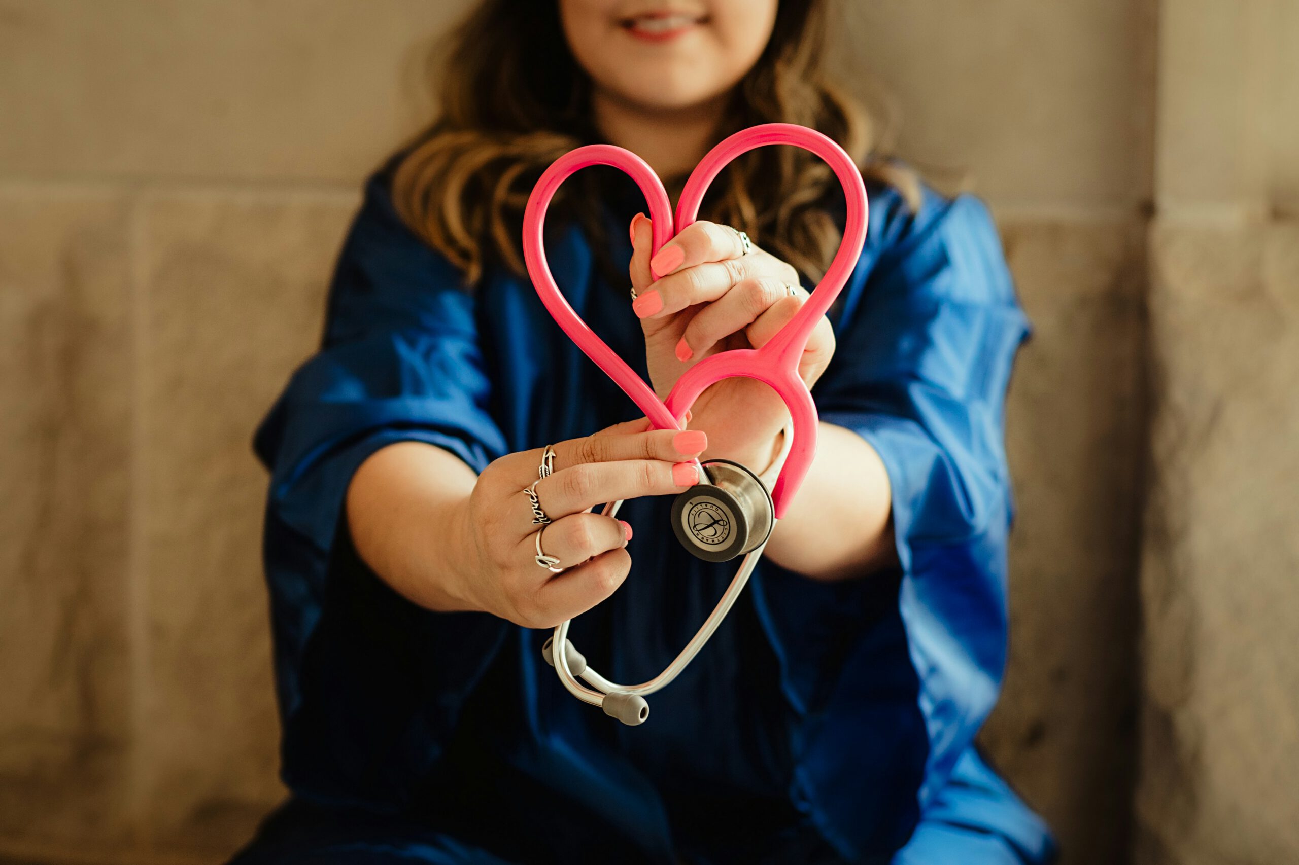 Woman holding a stethoscope in the shape of a heart.